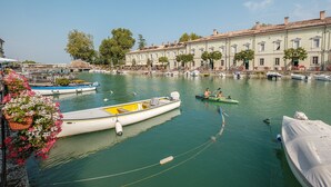 A canal with boats, a row of buildings, and a clear sky. - Near Gardaland, 2 minutes from the lake, in the heart of Peschiera del Garda! Xenia19 (Peschiera del Garda)