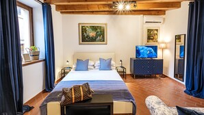 A hotel room with a large bed, a TV, a dresser, and a window with curtains. - Near Gardaland, 2 minutes from the lake, in the heart of Peschiera del Garda! Xenia19 (Peschiera del Garda)