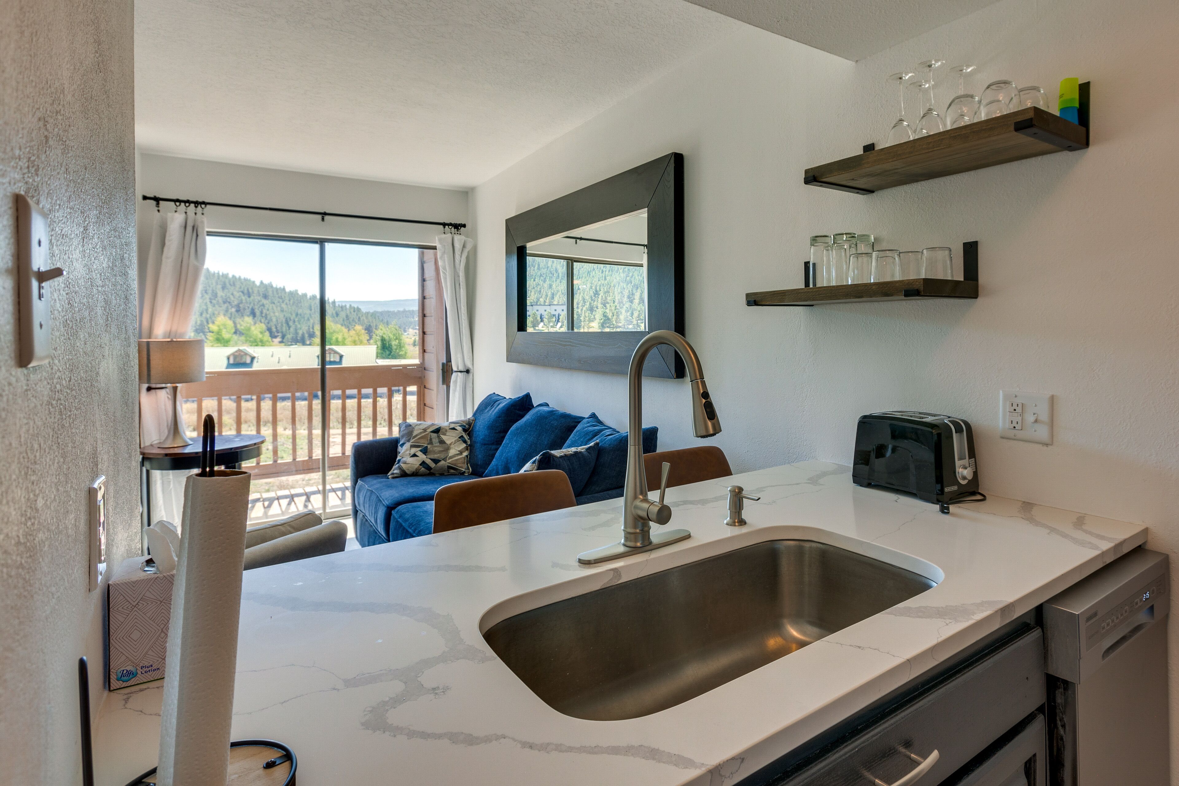 Una cocina moderna con un lavamanos grande, un tostador y una ventana con vistas a una terraza.
