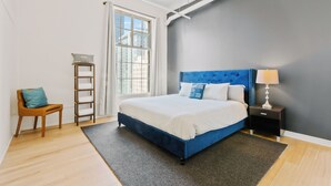 Une chambre à coucher avec un lit, une table de chevet, une chaise, une échelle et une fenêtre.