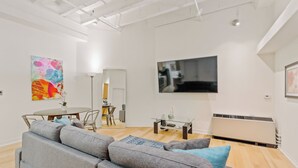 Un salon moderne avec un canapé gris, une table basse, un téléviseur à écran plat et un tableau accroché au mur.