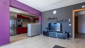 A modern kitchen with stainless steel appliances, a grey island, and red cabinets. - Pet friendly apartment in Stasevica (Stasevica)