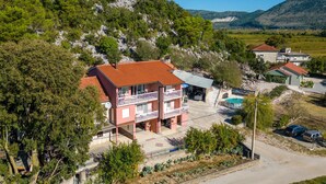 A two-story building with a red-tiled roof, a balcony, and a swimming pool. - Pet friendly apartment in Stasevica (Stasevica)