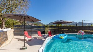 A swimming pool with red lounge chairs and umbrellas, surrounded by a stone wall and a wooden fence. - Pet friendly apartment in Stasevica (Stasevica)