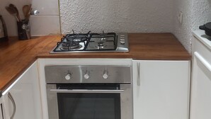 A kitchen with a gas stove, oven, white cabinets, and a wooden countertop.