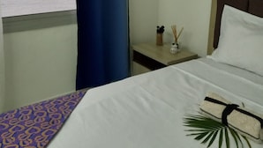 A hotel room with a bed, a nightstand, a window with a curtain, and a view of the sea.