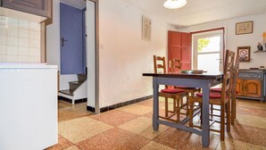 Een keuken met een witte koelkast, een eettafel met stoelen en een trap naar een andere kamer.