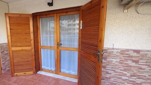 Una porta in legno con un vetro, un pavimento piastrellato e un muro in pietra.