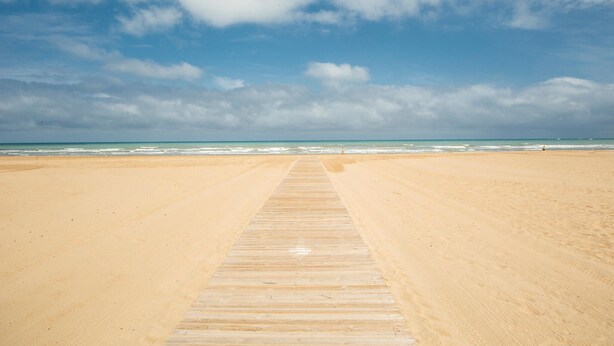 A beach with a wooden boardwalk leading to the water. - Gorgeous apartment in Grau i Platja with WiFi (Grau i Platja)