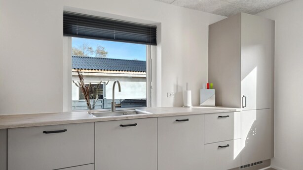 Eine moderne Küche mit großem Fenster, weißen Schränken und einer integrierten Spüle.