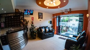 Un área de recepción con mostrador, asientos y televisor.