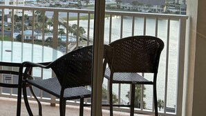 A balcony with two chairs and a table, overlooking a beach with buildings and a sunset. - BEAUTIFUL GULF VIEWS, 4 MIN WALK to BEACH  MANY UPGRADES SUNSETS ARE AWESOME (Miramar Beach)