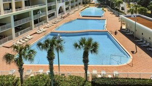 A hotel with two swimming pools, a covered walkway, and a view of the surrounding buildings. - BEAUTIFUL GULF VIEWS, 4 MIN WALK to BEACH  MANY UPGRADES SUNSETS ARE AWESOME (Miramar Beach)