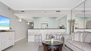A modern living room with a sofa, a coffee table, and a TV. - BEAUTIFUL GULF VIEWS, 4 MIN WALK to BEACH  MANY UPGRADES SUNSETS ARE AWESOME (Miramar Beach)