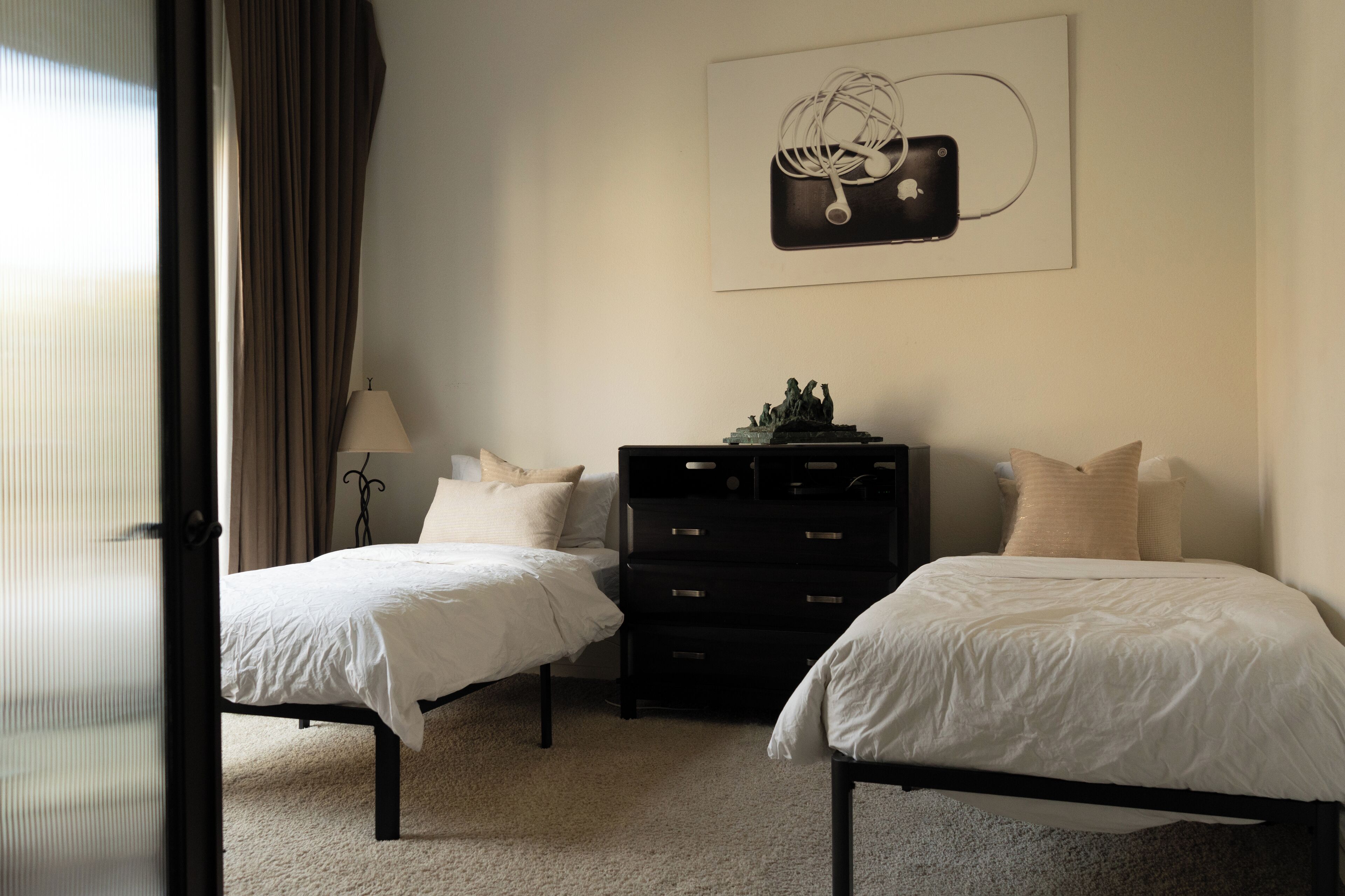 A bedroom with two beds, a dresser, and a wall-mounted artwork.
