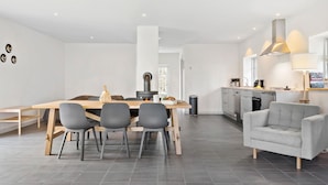 A modern kitchen with a dining area, grey chairs, and a grey sofa. - 4 bedroom lovely home in Næstved (Næstved)