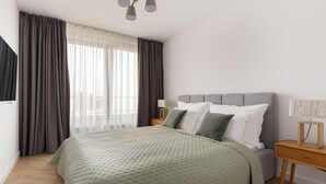 A modern bedroom with a large bed, grey headboard, and a wooden nightstand with a lamp. - 2 bedroom lovely apartment in Gdynia (Gdynia)