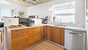 A modern kitchen with wooden cabinets, a Bosch dishwasher, and a window with blinds. - Amazing home in Samsø with Wi-Fi (Samsø)