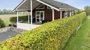 A wooden cabin with a covered porch, a small deck, and a well-maintained hedge. - Amazing home in Samsø with Wi-Fi (Samsø)