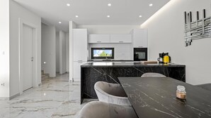 A modern kitchen with a marble countertop, a built-in TV, and a coffee maker. - Beach front home in Vodice (Vodice)