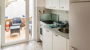 A kitchen with white cabinets, a sink, and a window overlooking a patio area with outdoor furniture.