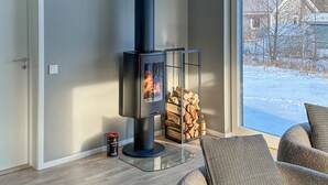 A modern living room with a glass-top coffee table, a sofa, and a wood-burning stove.