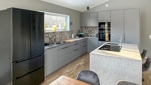 A modern kitchen with a built-in refrigerator, a sink, and a dining area with a table and chairs.