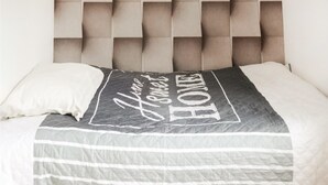 A bed with a grey and white striped bedspread and a pillow with the text "Home Sweet Home." - Cozy apartment in Gdynia with WiFi (Gdynia)