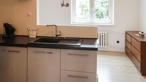A kitchen with a black countertop, stainless steel cabinets, a sink, and a window providing natural light. - Cozy apartment in Gdynia with WiFi (Gdynia)