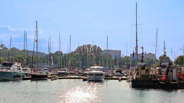 A marina with multiple boats docked, a clear sky, and buildings in the background. - Cozy apartment in Gdynia with WiFi (Gdynia)
