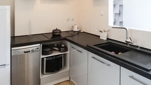 A modern kitchen with stainless steel appliances, a black countertop, and white cabinetry. - Cozy apartment in Gdynia with WiFi (Gdynia)