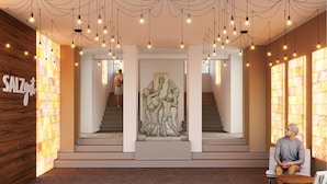 Un intérieur moderne avec un escalier central, une sculpture en pierre et une enseigne portant l’inscription « SALZGUT ».