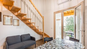 A modern interior with a wooden staircase, a gray sofa, and a glass table with a geometric pattern.