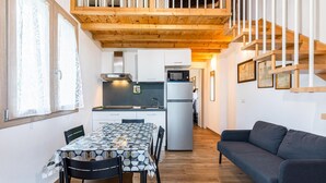 A compact kitchen with a dining table and chairs, a refrigerator, and a microwave.