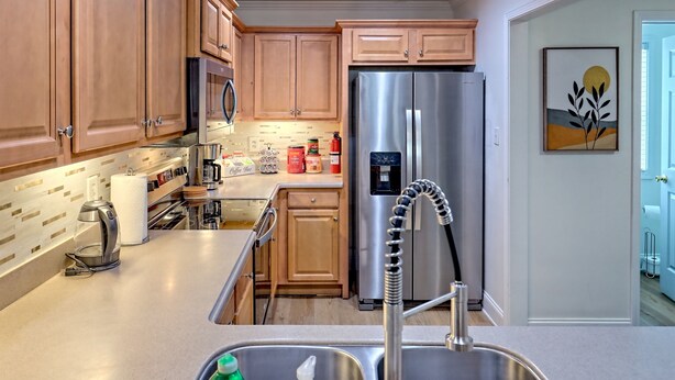 A modern kitchen with wooden cabinets, stainless steel appliances, and a built-in water dispenser. - Downtown Helen | Park and Walk (Helen)
