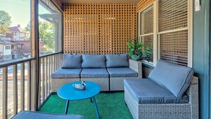 A balcony with a grey sofa, a small round table, and a potted plant. - Downtown Helen | Park and Walk (Helen)