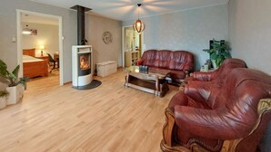 A living room with a fireplace, leather sofas, a coffee table, and a ceiling fan.
