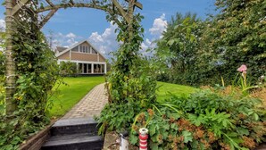 A pathway leading to a house with a wooden pergola and a garden.