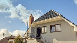 A two-story house with a tiled roof, a chimney, and a small balcony with a metal railing. - 3 bedroom lovely apartment in Wiselka (Wiselka)