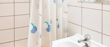 A bathroom with a white sink, a mirror, and a shower curtain with a circular pattern.