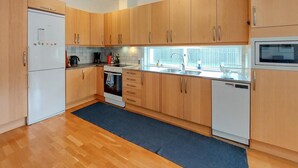 Eine kleine Küche mit Holzschränken, einem weißen Kühlschrank, einem Herd, einem Spülbecken und einem Geschirrspüler.