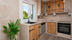 Une cuisine moderne avec des meubles en bois, un four encastré et une fenêtre qui laisse entrer la lumière naturelle.