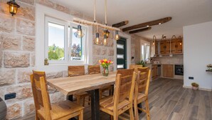 Une cuisine rustique aux murs de pierre, aux meubles en bois et offrant une vue sur l’extérieur grâce à de grandes fenêtres.