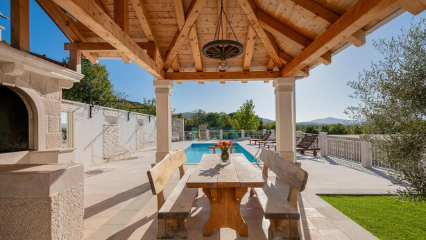 Un espace extérieur abrité doté d’une piscine, de murs en pierre et d’une pergola en bois.