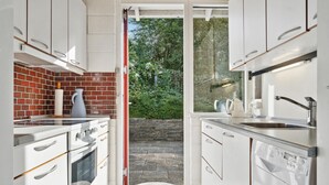 A modern kitchen with white cabinets, a brick backsplash, and a view of a garden through a glass door. - 3 bedroom gorgeous home in Malling (Malling)