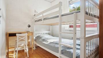 A bunk bed room with a desk and chair, a window, and a view of the outside.