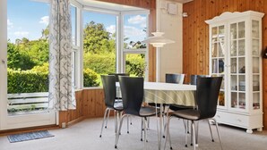 A dining area with a table and chairs, a cabinet with glass doors, and a view of greenery outside. - 3 bedroom gorgeous home in Malling (Malling)