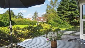 A patio with a table, a potted plant, and a large umbrella.