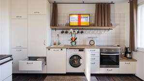 A compact kitchen with a washing machine, oven, and a small sink.