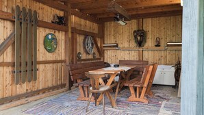 A rustic wooden room with a wooden bench, a table, and chairs. There are wooden beams on the ceiling and a wall-mounted heater.